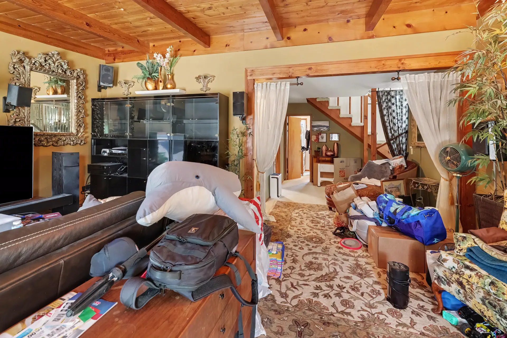 Open-plan living and dining under exposed timber beams, photographed in its current occupied condition.